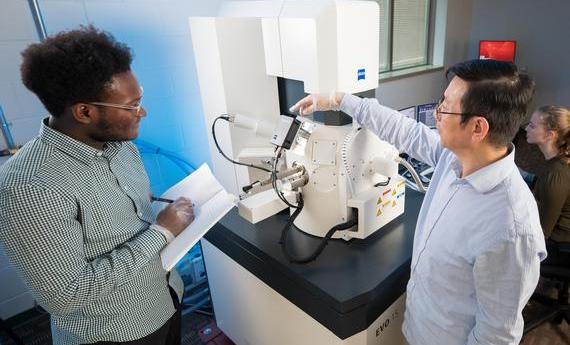 Two people using an electron microscope in 51's College of Liberal Arts