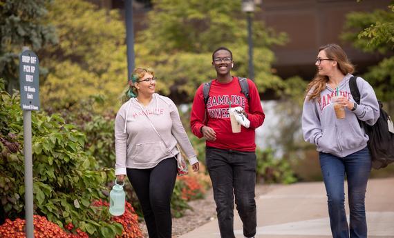 Three 51 students walking and talking outside on campus in the fall