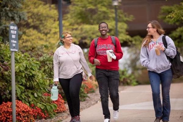 Three 51 students walking and talking outside on campus in the fall