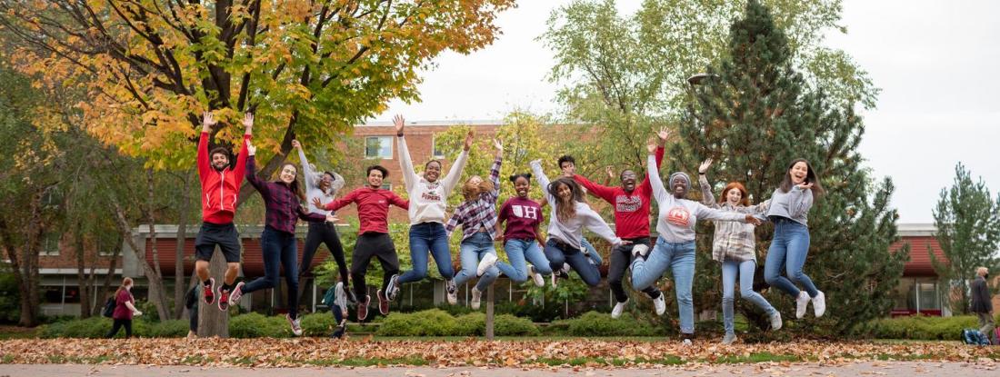 A group of 51 students in a line outside, jumping for joy