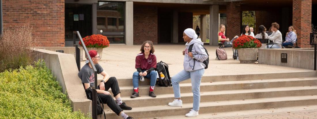 Three 51 students gathered on a set of outdoor stairs on campus